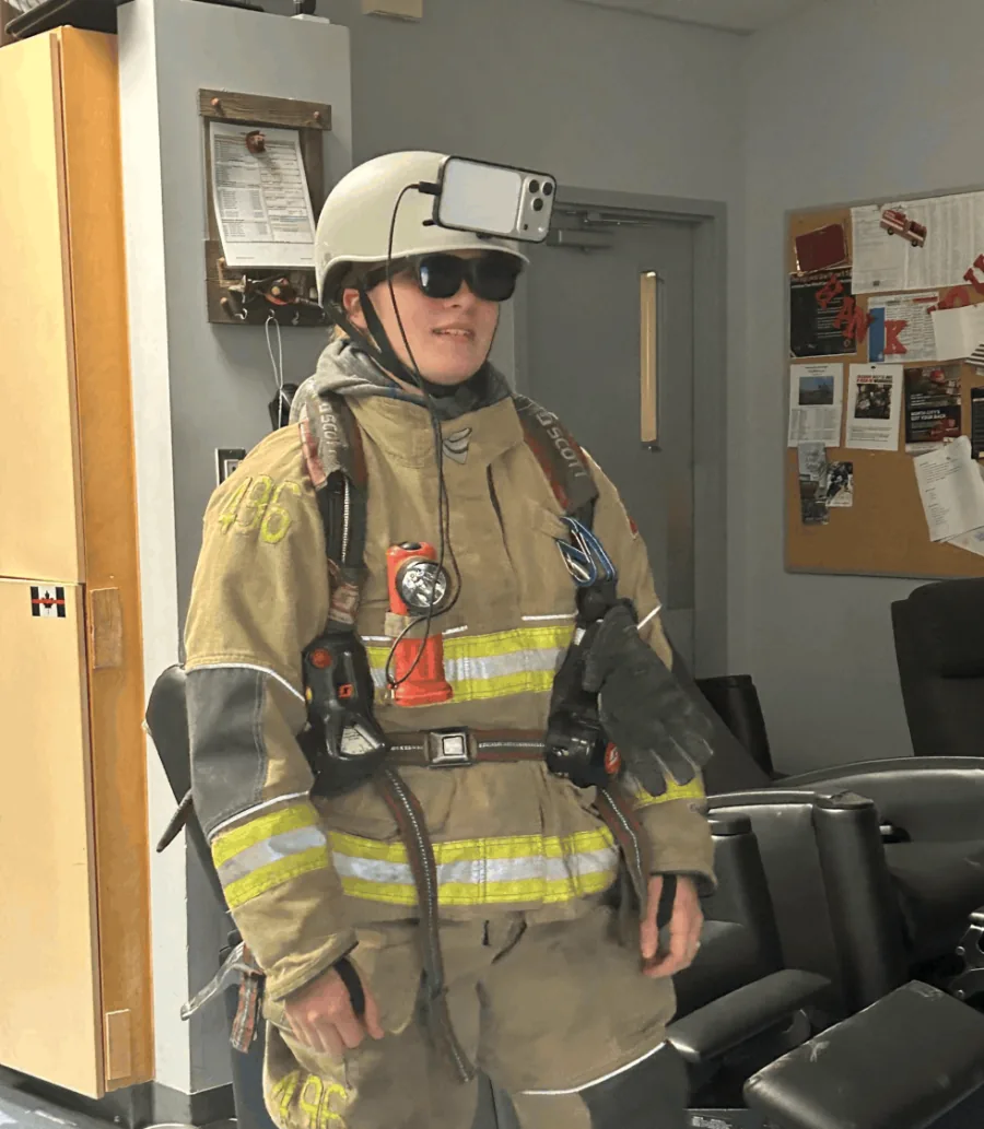 A firefighter in full turnout gear wearing a helmet-mounted Ember test rig.